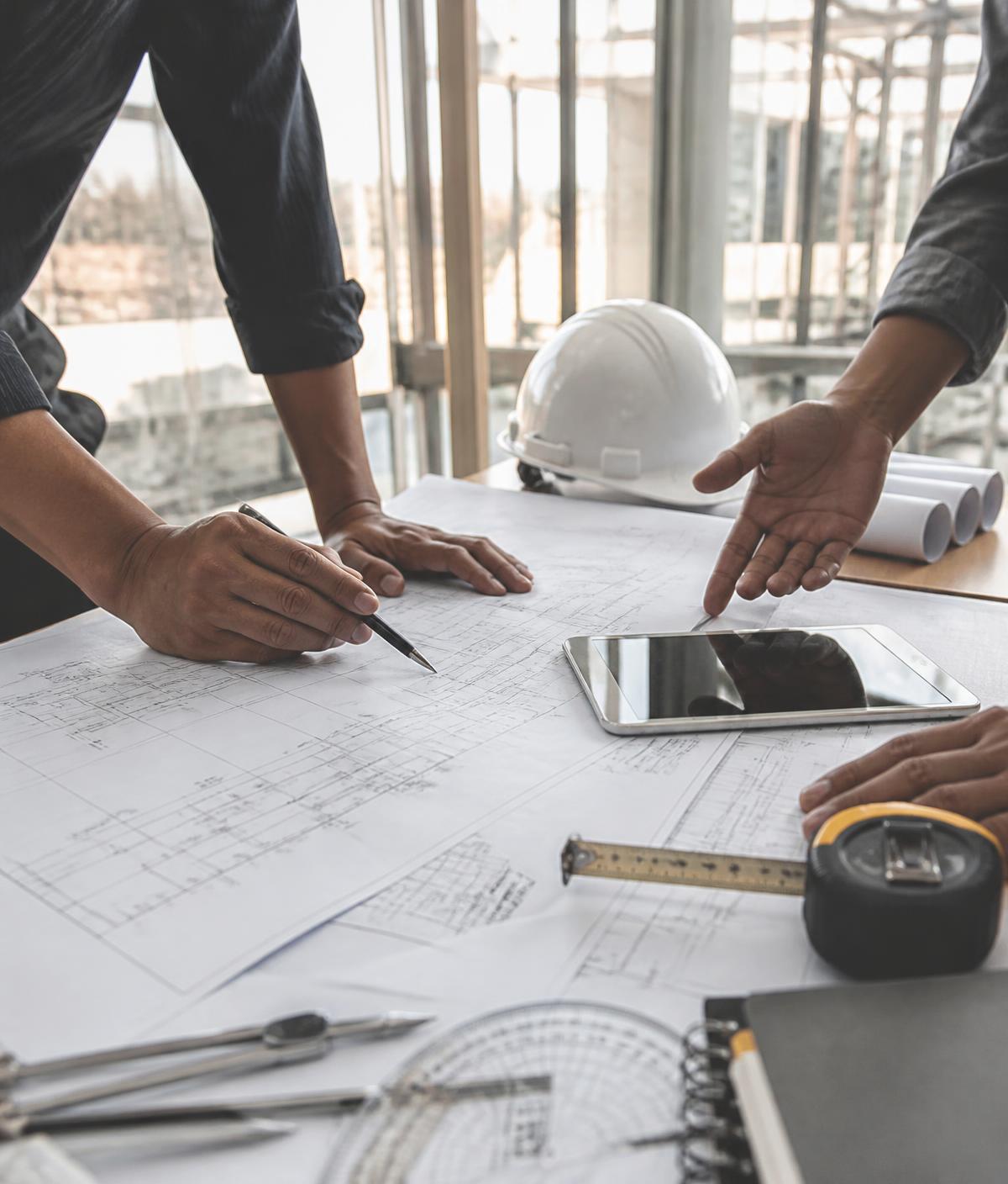Equipe de engenharia analisando projetos técnicos em obra corporativa